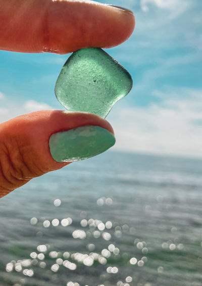 Et hav og et stykke havsglas der holdes mellem to fingre
